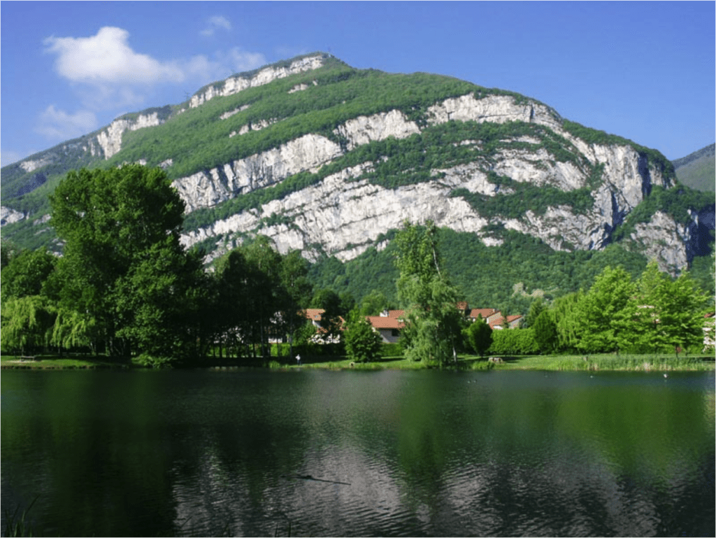 Photo du plis de Sassenage. En regardant attentivement la falaise, vous observerez que les différentes strates de roches, initialement horizontales lorsqu’elles se sont déposées dans la mer alpine, sont maintenant basculées, plissées, formant ainsi un très bel anticlinal. Une observation attentive permet également de mettre en évidence une discontinuité dans les strates sédimentaires de la partie droite du pli. Cette discontinuité marque l’existence d’une faille